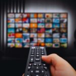 Persona che usa telecomando per scegliere quale serie guardare