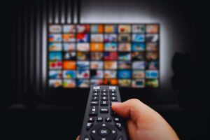 Persona che usa telecomando per scegliere quale serie guardare