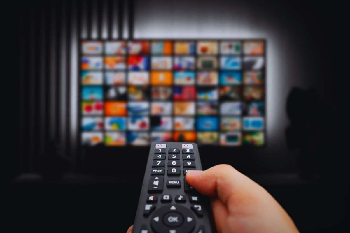Persona che usa telecomando per scegliere quale serie guardare