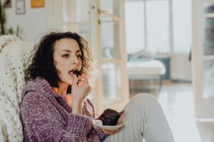 donna seduta sul divano che mangia un muffin
