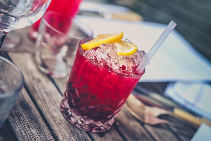 bicchiere con dentro un cocktail rosso e una cannuccia di plastica