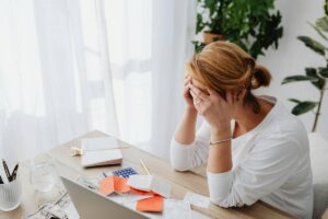 donna seduta che legge dei fogli con le mani sulla testa
