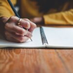 Mano di ragazza che scrive con matita sul quaderno