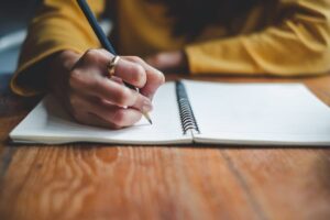Mano di ragazza che scrive con matita sul quaderno